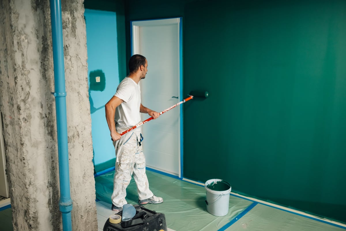 Professional painter applying green paint to a wall during a home renovation