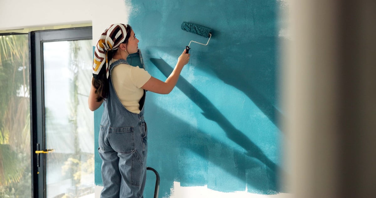 Woman painting an interior wall in a home during a renovation